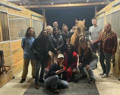a group of students standing in a horse barn