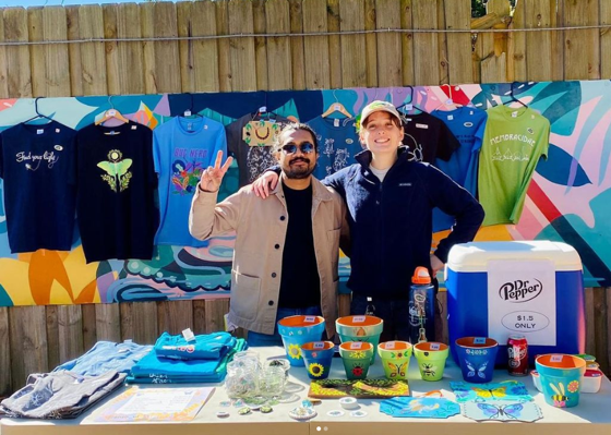 two students standing behind a merchandise table