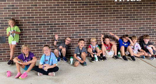 4-h students sitting along a brick wall. 